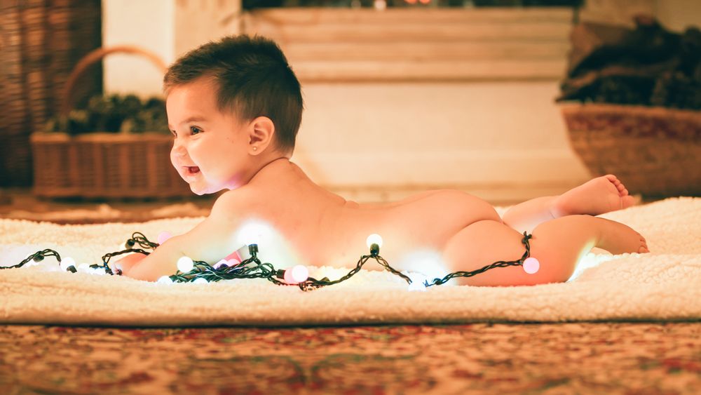 Baby playing with light garland on Christmas Day