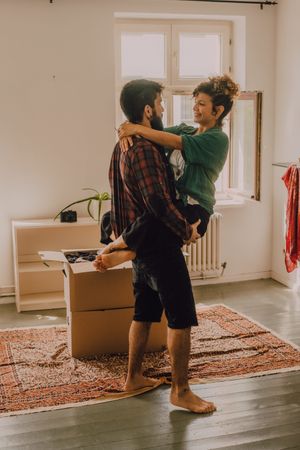 Happy couple embracing in room next to cardboard boxes