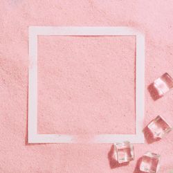 Pink sand with paper square outline and ice cubes