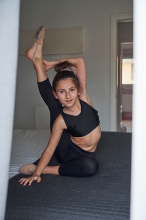 Flexible girl stretching body on bed