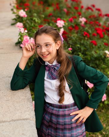 Girl in school uniform smiling, hand on glasses