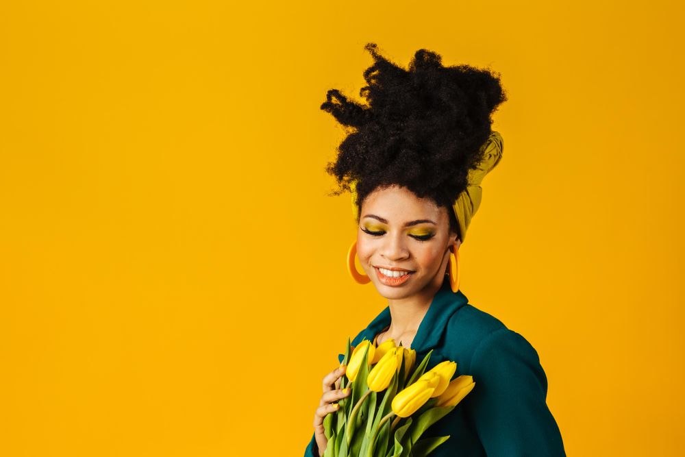 Portrait of smiling Black woman with tulips, earrings and head wrap