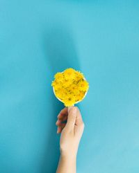 Hand holding mug with yellow flowers in water