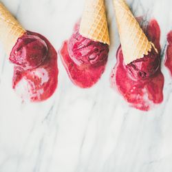 Cones of dark berry ice cream melting on marble slab, square crop with copy space