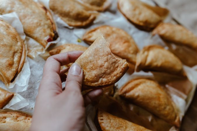 hand holding and Baking tray with composed freshly baked pies patty