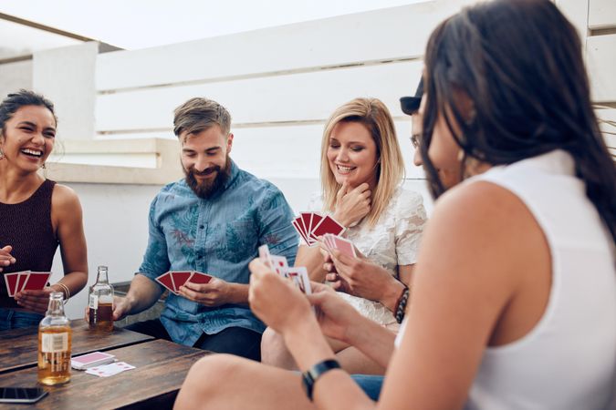Group of friends sitting at a wooden table and playing cards