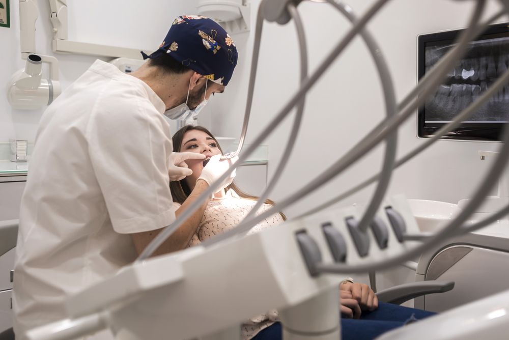 Male dentist working on mouth of female teenage patient