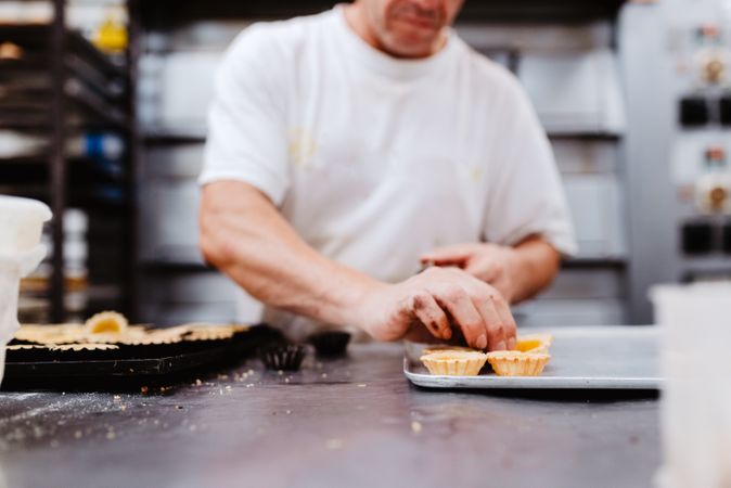 Crop confectioner decorating small cakes