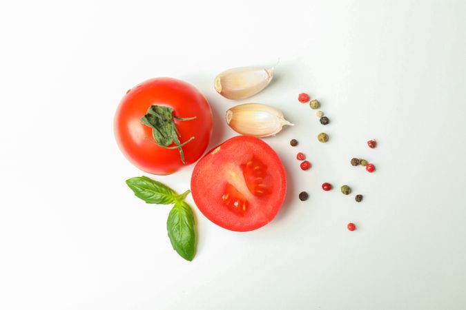 Fresh cherry tomatoes with basil, spices and garlic on blank background, space for text and top view. Ripe vegetables