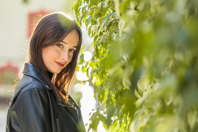 Charming woman beside bush leaves on street