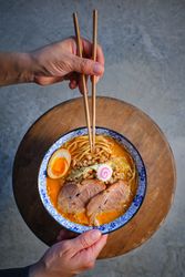 Faceless person having dinner with Asian noodle soup