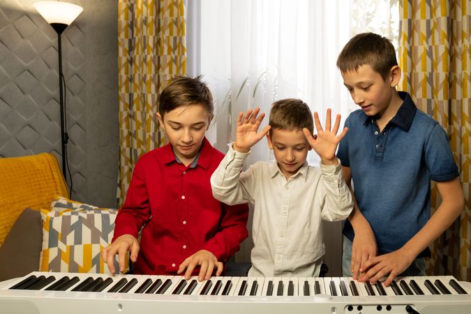 Three boys having fun while experimenting with the piano keys