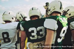 Rearshot of a football team huddling before a game 4M2xab