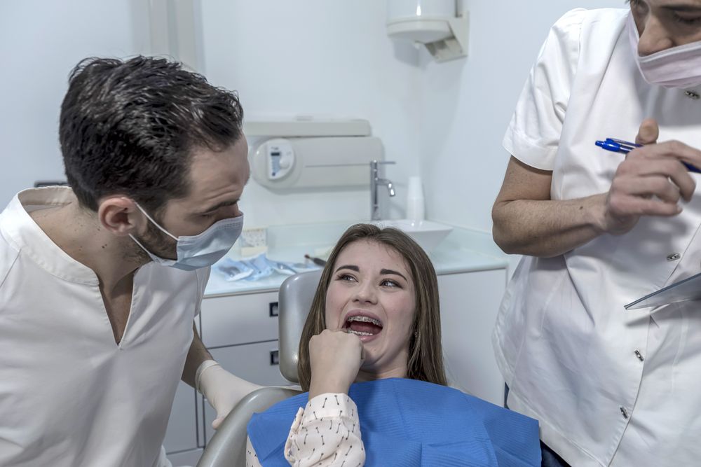 Teen female with toothache pain sitting to dental chair
