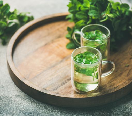 Mint tea with fresh mint leaves on wooden tray, close up, with copy space