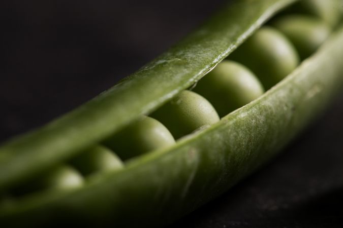 Fresh peas and pea pods on dark background
