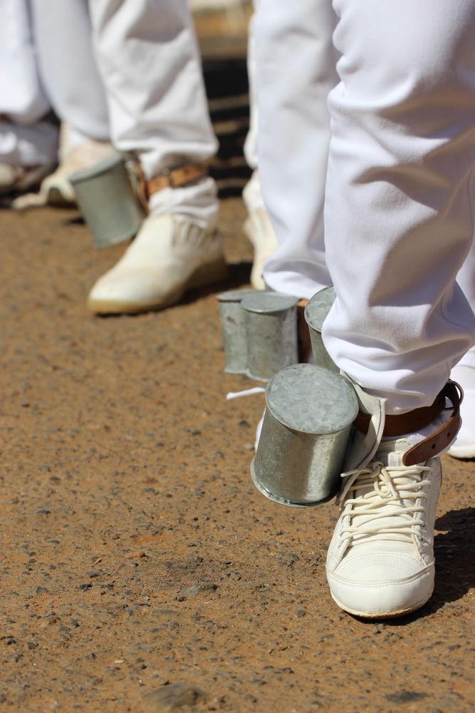 People in light outfit with cans to their leg