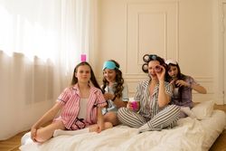 Girls and mom play with curlers in a cozy bedroom.