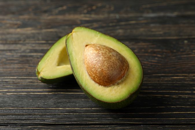 Ripe fresh avocado on wooden background, close up
