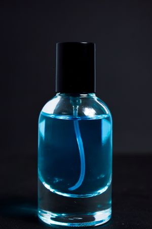 Light blue perfume bottle in dark studio