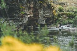 Confident man fishing with rod while standing in river stream