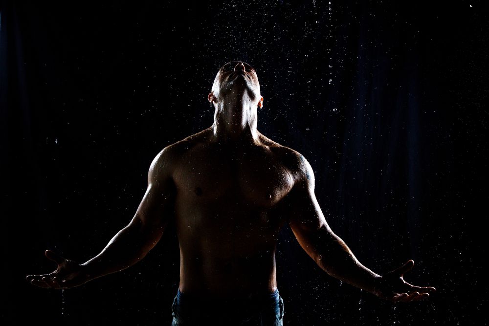 Muscular male under rain