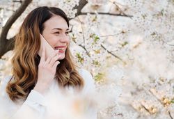 Woman answering phone call near blooming trees