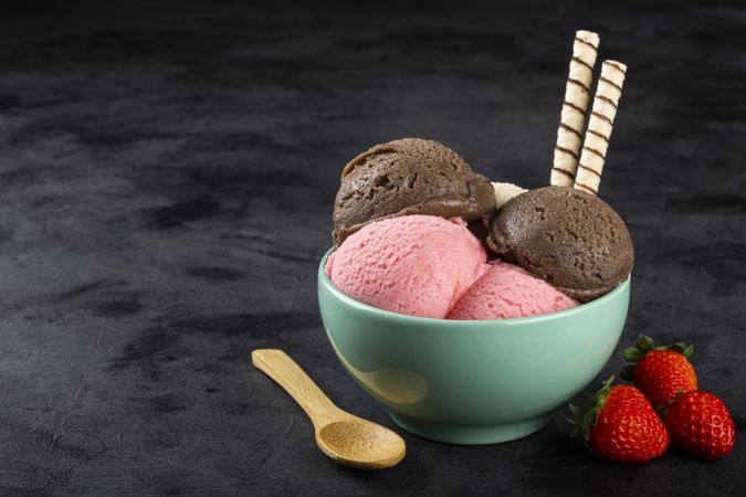 Bowl with Neapolitan ice cream on dark background.
