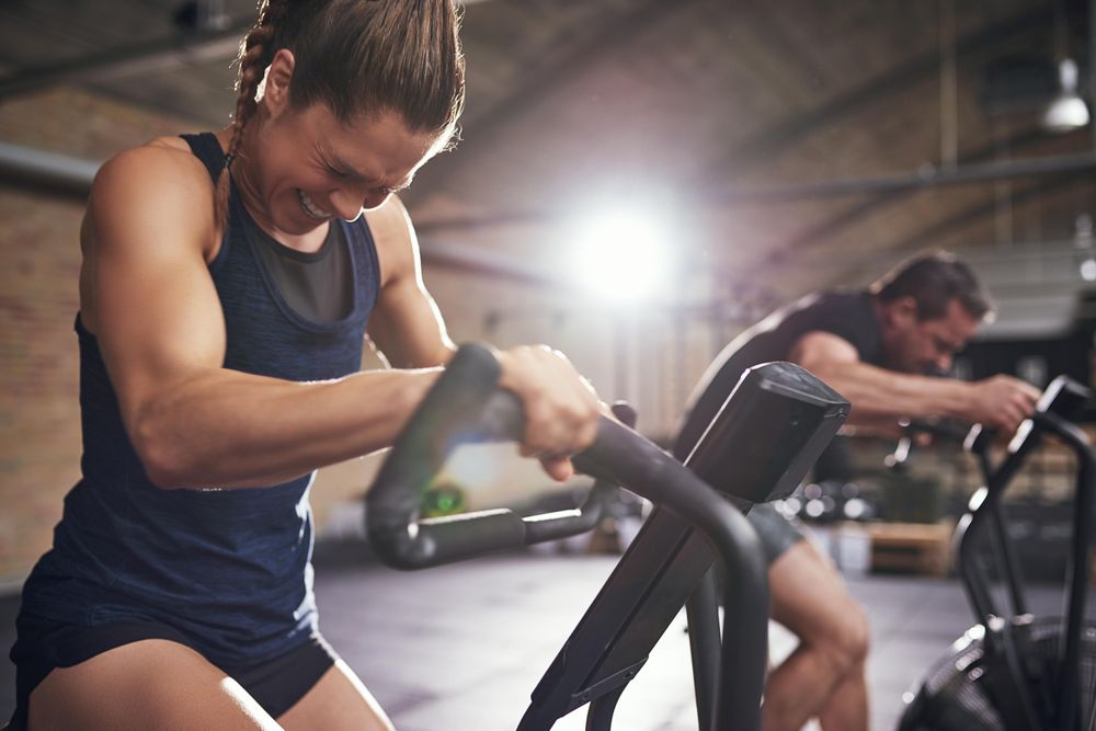 Tough woman exerting herself on indoor cycling bike