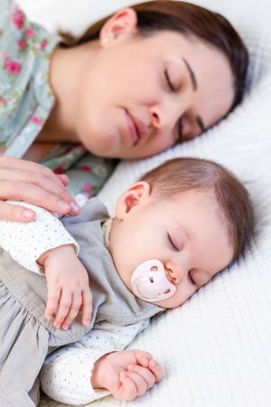 Young mother and her baby girl sleeping in the bed