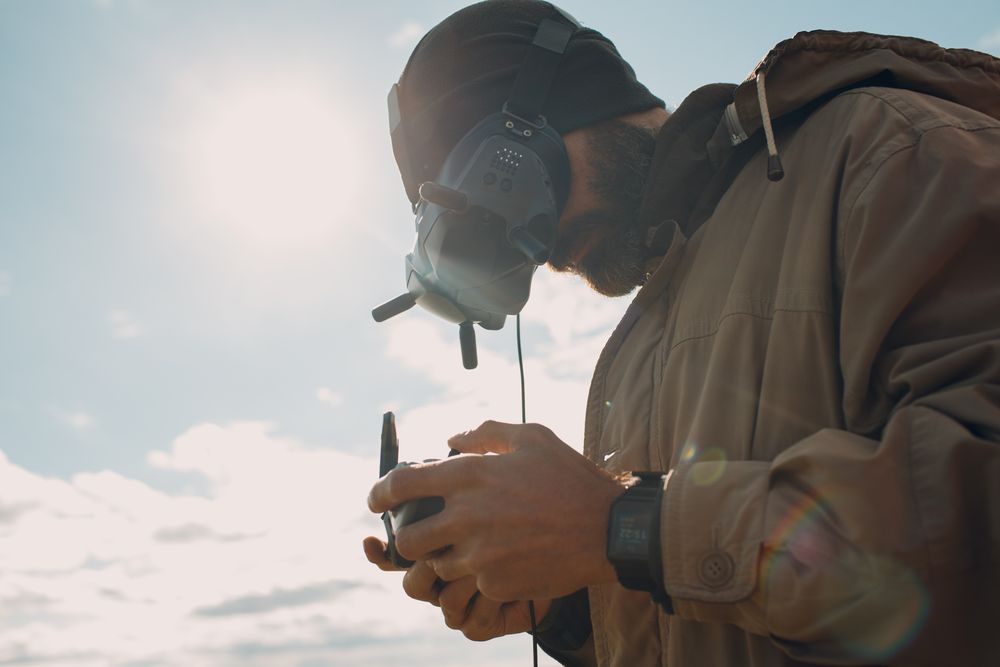 Adult man wearing goggles and holding a controller standing outdoor