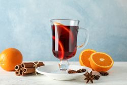 Mulled wine, orange and cinnamon on blue wooden background, space for text