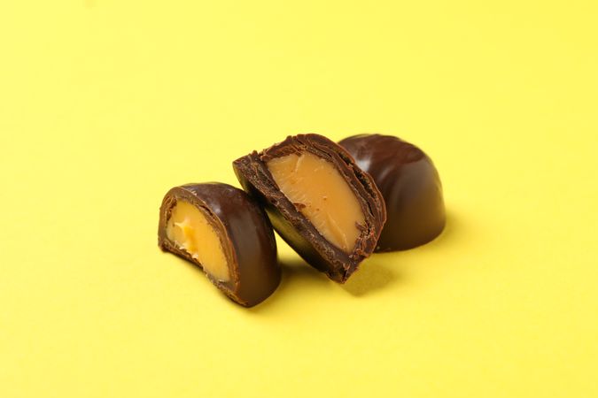 Tasty chocolate candies on yellow background, close up