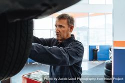 Mechanic fastening the wheel of a car in service station 0yLMLb