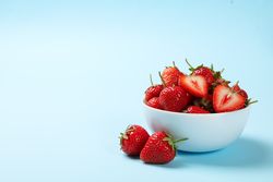 Bowl with tasty strawberry on blue background. Summer berry