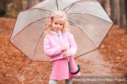 Girl in pink outfit holding an umbrella standing outdoor 0P2wg4