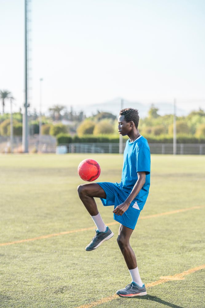 Black teenager juggling football ball