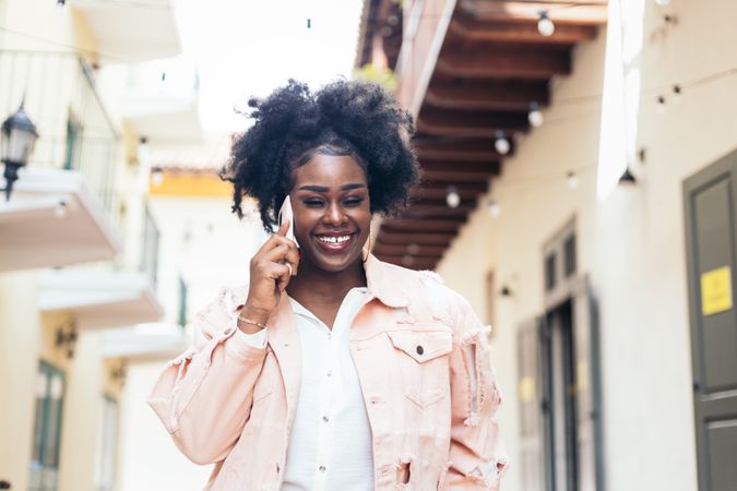 Stylish Black woman walking on the city street talking on the phone