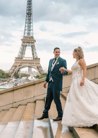 Happy newlyweds walking downstairs holding hands in Paris