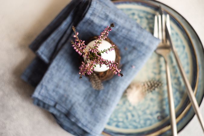 Top view of Easter table setting with egg shell and heather on blue plates