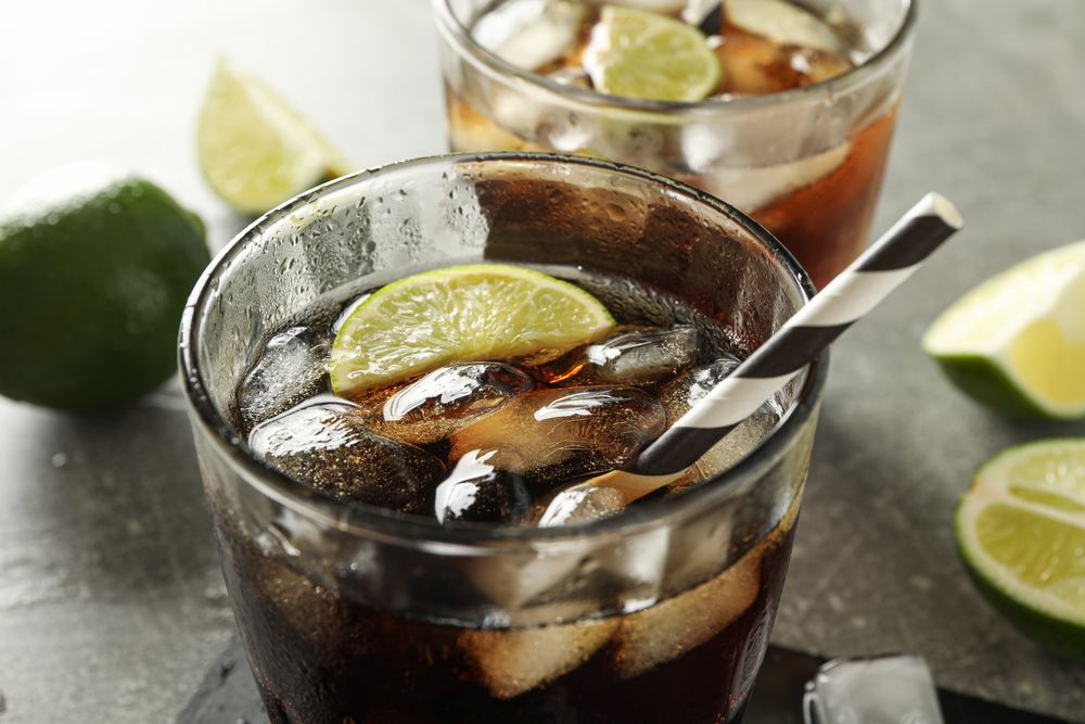 Glasses with cold cola and citrus on grey table, closeup