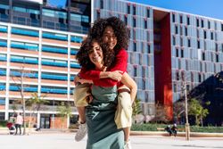 Female friends piggy backing outside on sunny day
