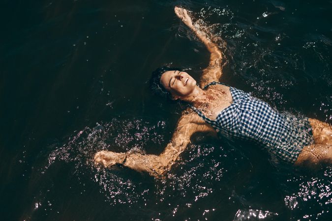 Woman swimming in a lake on a sunny day wearing a bikini