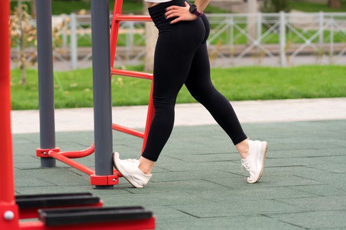 Woman stretching leg against fitness equipment