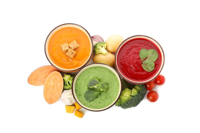 Top view of three vegetable soups and ingredients