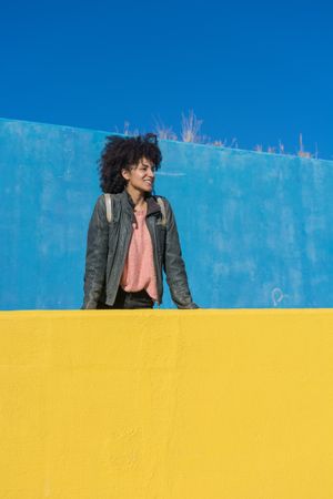 Black woman with afro hair leaning against brightly colored wall