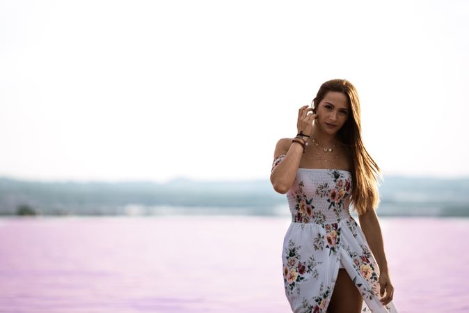 Peaceful woman in white dress walking ankle deep in pink lake