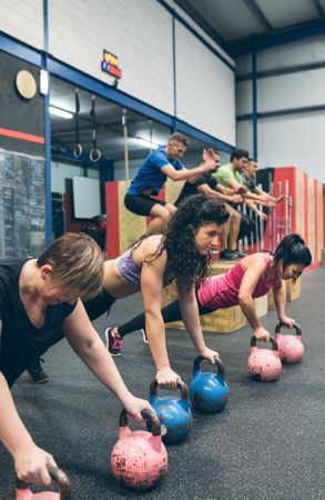 Sportswomen doing push-ups with kettlebells