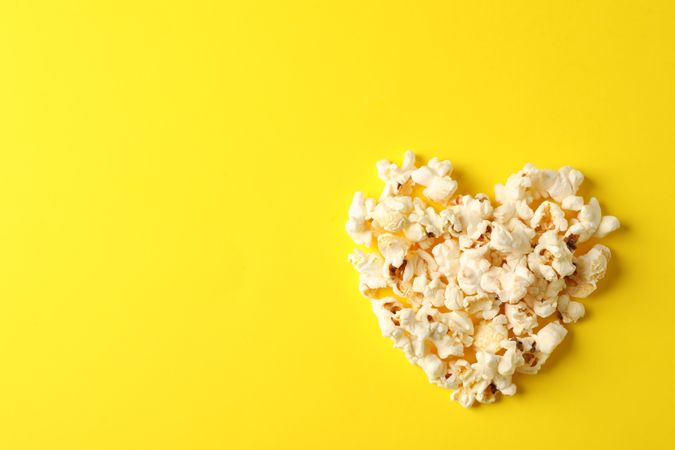 Flat lay composition with popcorn heart on yellow background, space for text