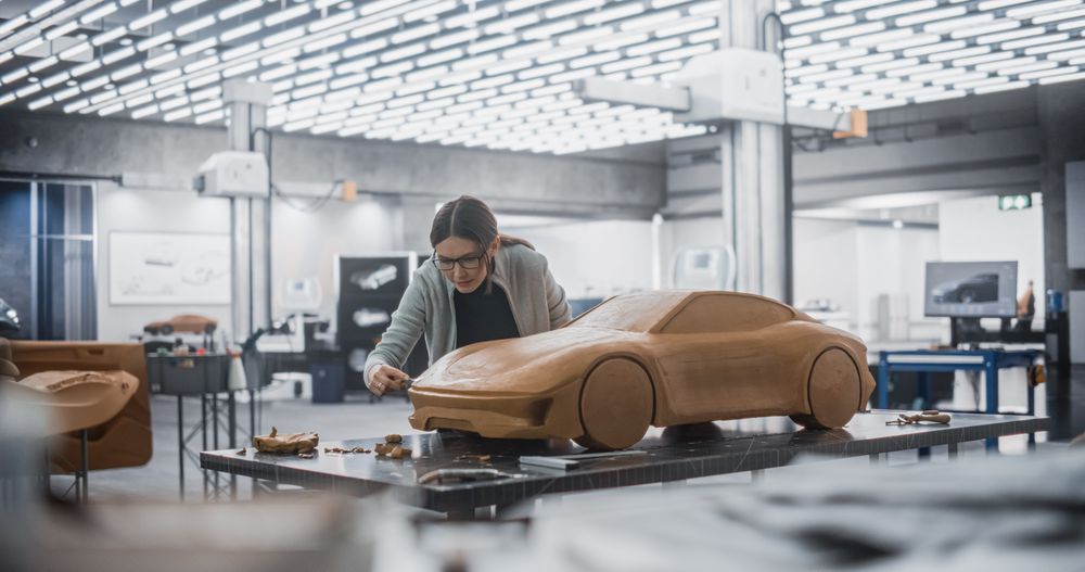 Female Designer Using Spatula to Smooth the Prototype Model of a Modern Electric Sportscar